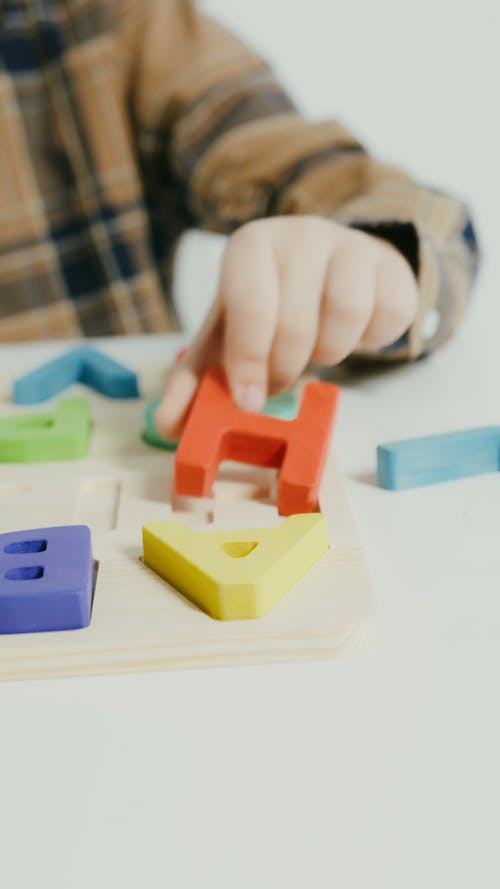 Person Playing with Wooden Alphabet Letters
