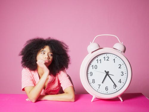 A Bored Girl Waiting With A Big Alarm Clock Besides Her