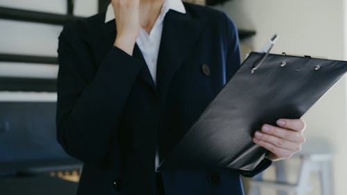 A Woman Talking on a Cellphone while Looking at a Clipboard