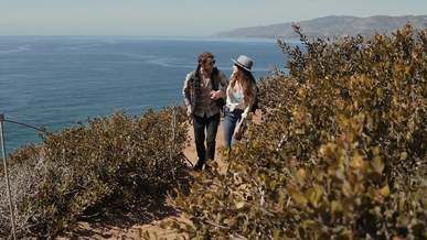 a couple holding each others hand while walking on a trail