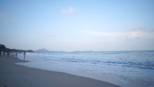 People Standing in Sea Shore Enjoying Waves