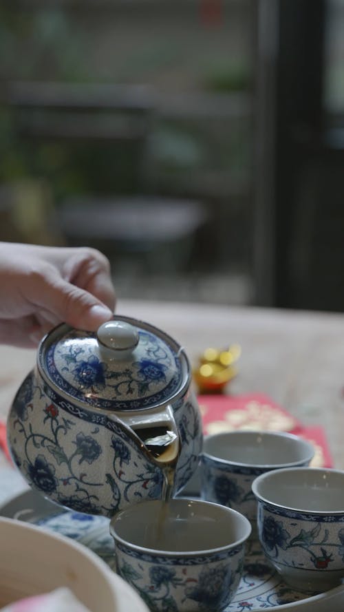 a Person Pouring Tea in a Ceramic Cup