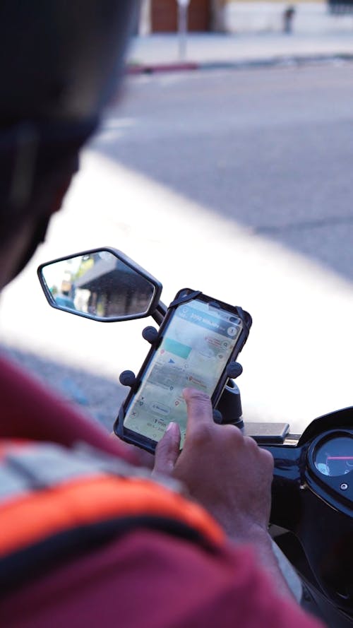 A Man Using the Map on His Phone that is Mounted on the Motorcycle