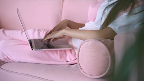 Close-Up View of a Person Sitting on a Couch while Using a Laptop