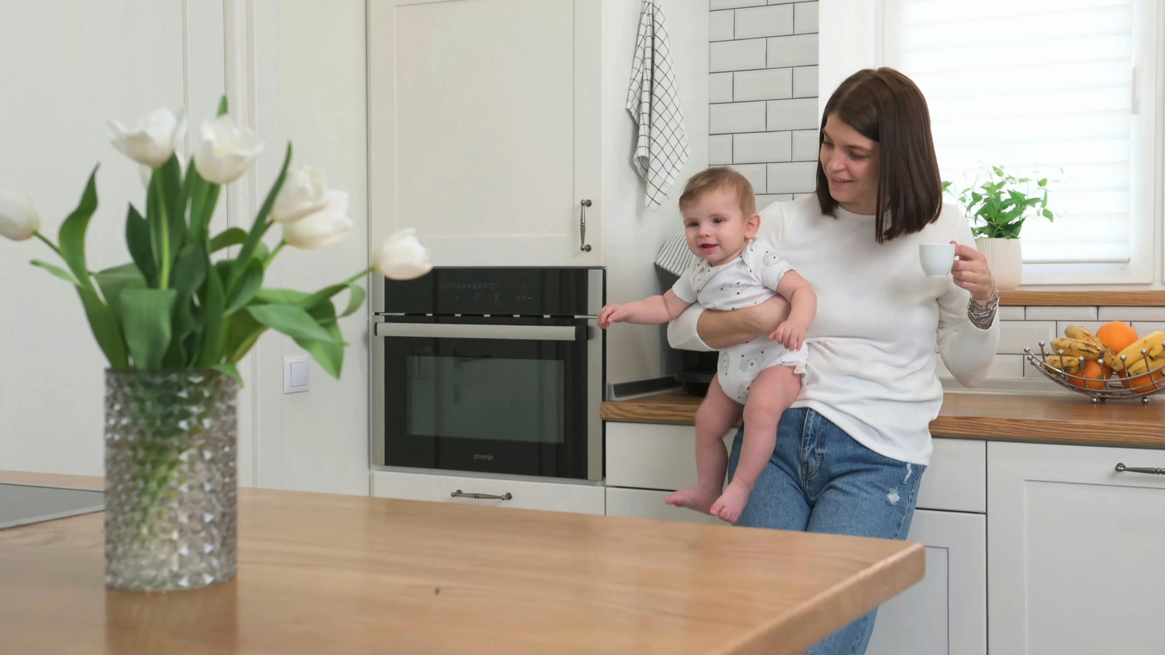 Woman Carrying a Baby While Drinking Coffee · Free Stock Video