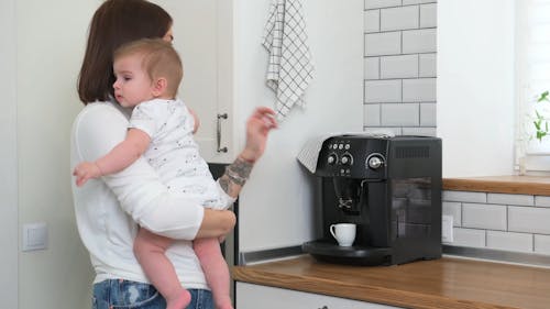 Woman Prepares Coffee While Holding Her Baby