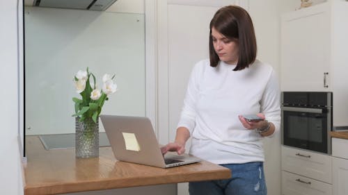 A Woman Using Electronics Devices In The Kitchen