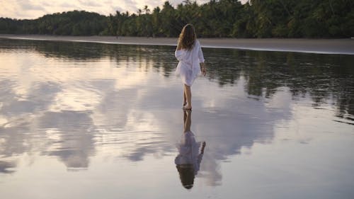 A Woman Walking on Wet Sand