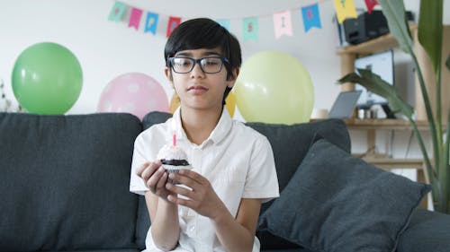 Boy Blowing the Lighted Candle on the Cupcake