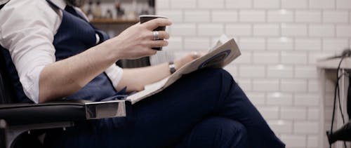 Businessman Reading a Newspaper and Drinking Coffee at the Barbershop