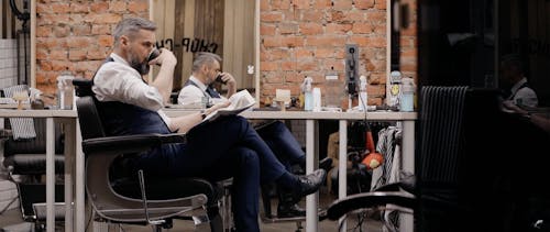 Businessman Reading a Newspaper and Drinking Coffee at the Barbershop