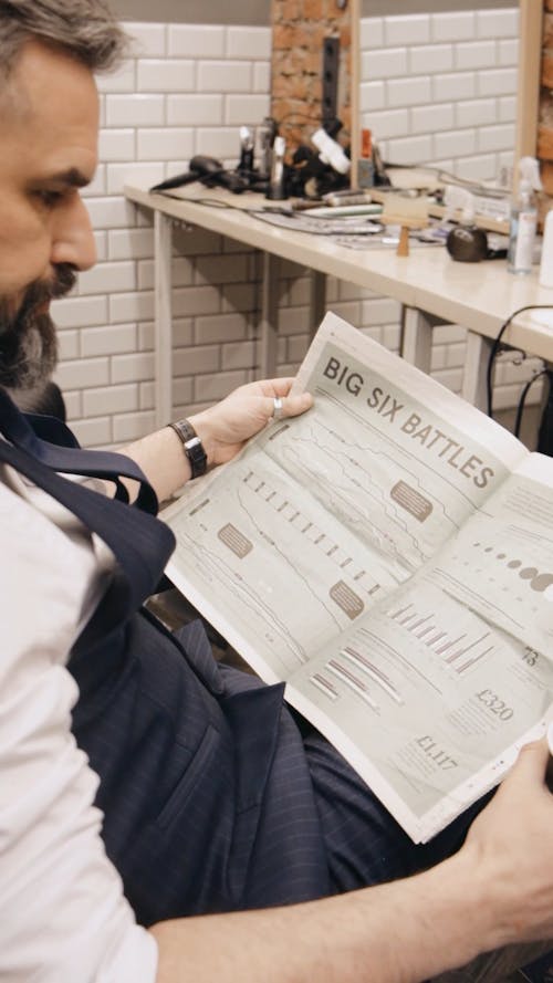 A Man Sitting while Reading a Newspaper in the Barbershop