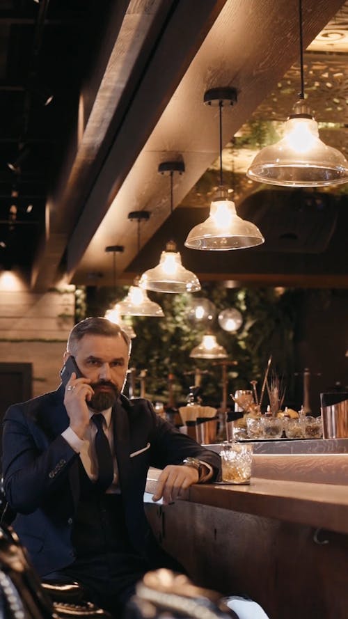 Businessman Talking on the Phone while Sitting on the Bar Counter