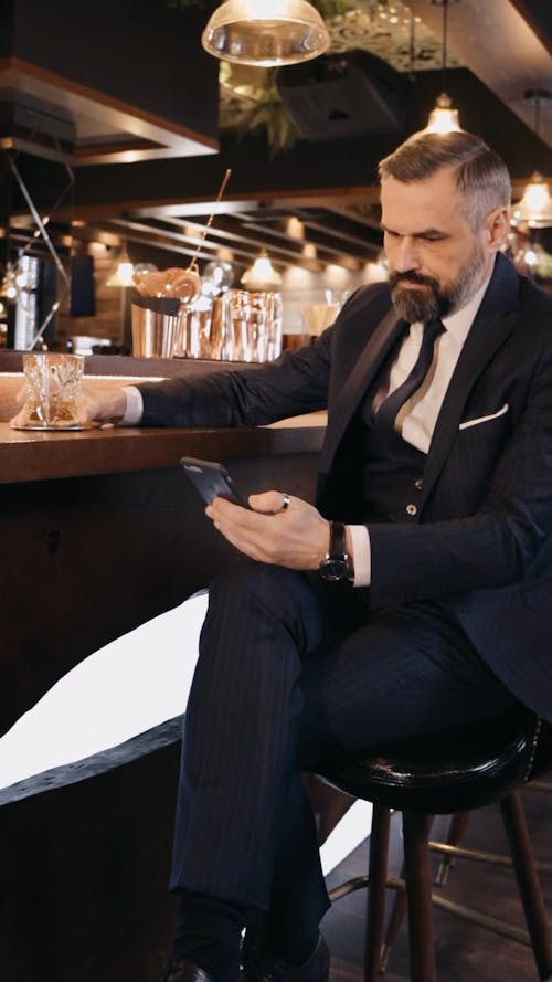 A Man Using Smartphone while Drinking at the Bar Counter
