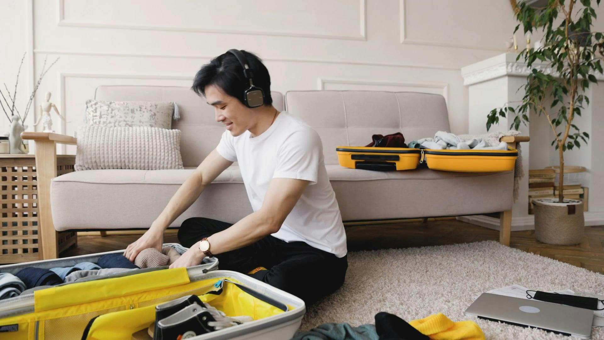 Man Listening to Music while Packing his Clothes in the Luggage · Free ...