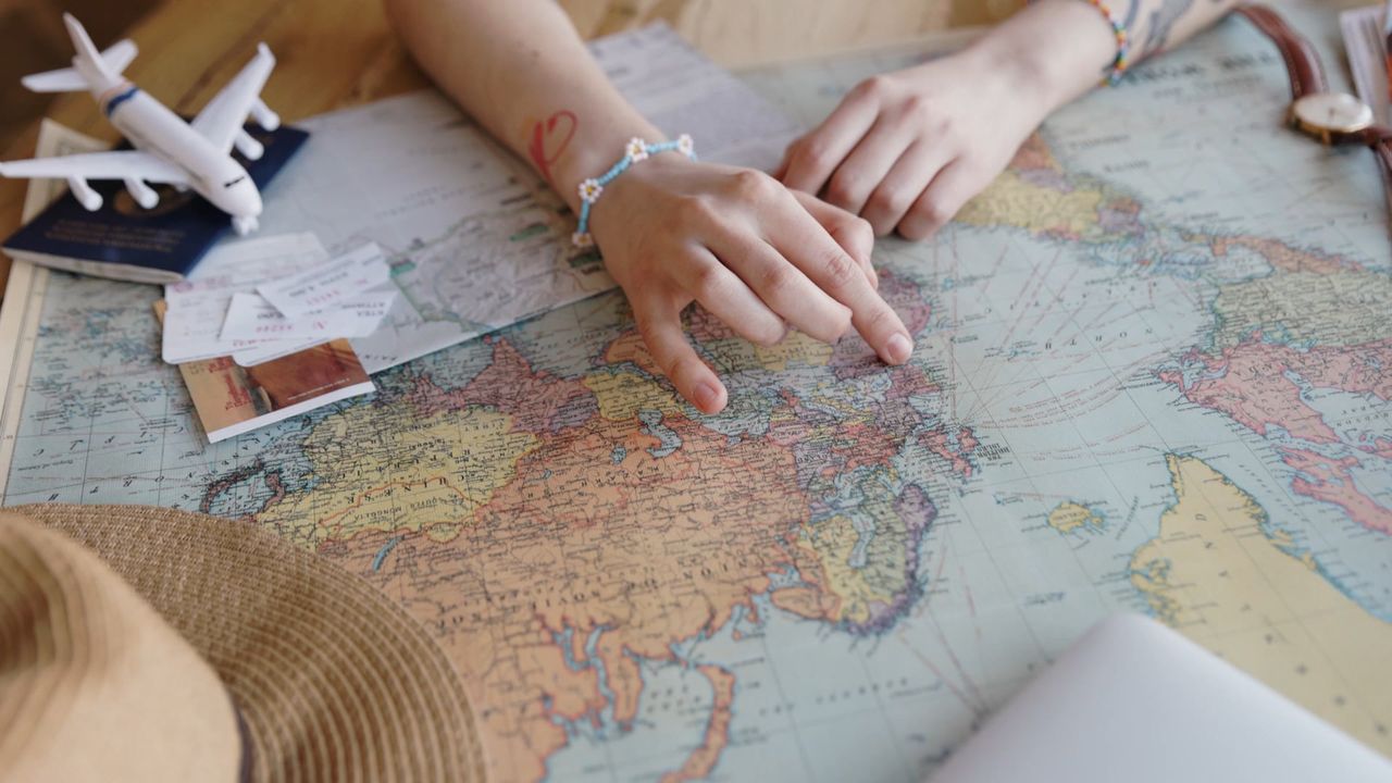 Hands planning routes across a world map for an international office opening