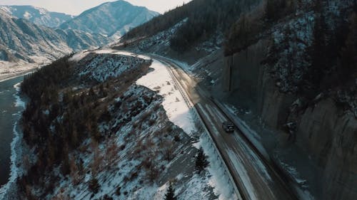 Car on Winter Road Among Mountains