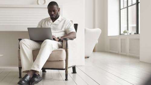 Man Sitting on a Chair while Using a Laptop