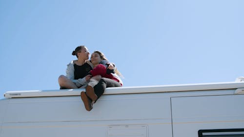 A Couple Kissing and Sitting on Top of a Caravan