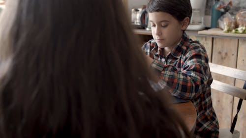 Boy Slicing Sausage on Plate