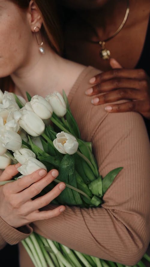 Two Women Hugging and Holding White Flowers