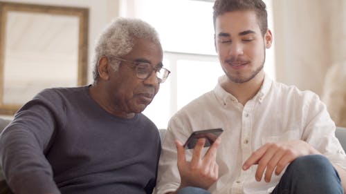 Man Holding Cellphone Beside an Elderly Man