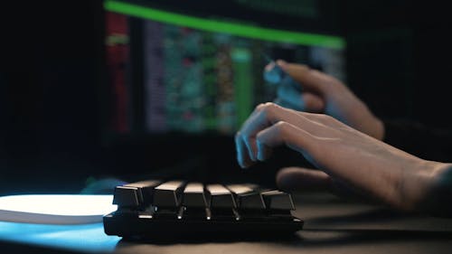 A Person Typing on a Computer Keyboard While Holding a Card