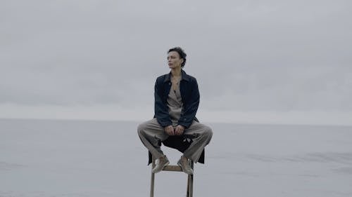 A Woman Sitting on a Chair Behind an Ocean