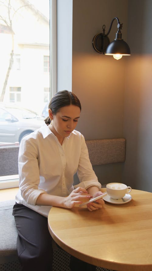 Woman at Table Typing on Phone