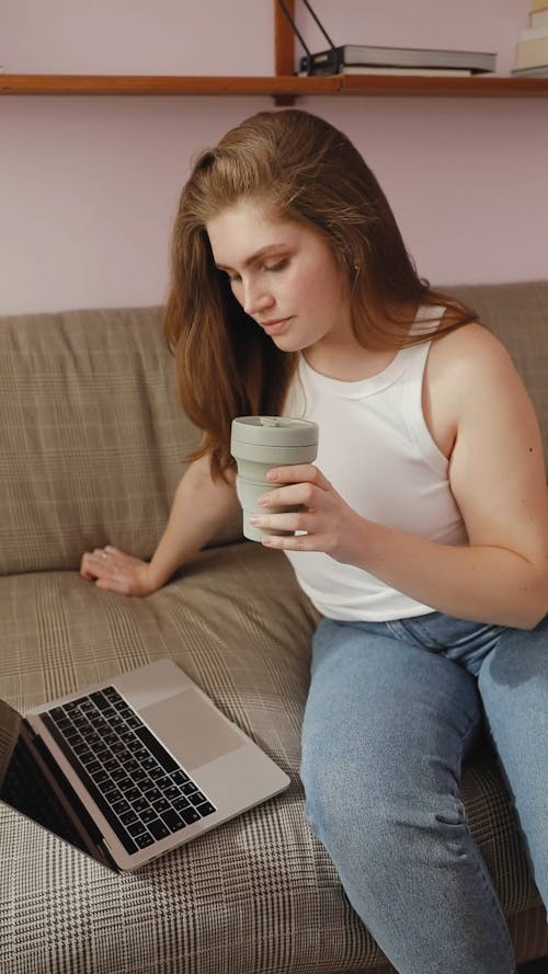 Woman Looking on the Laptop while Drinking