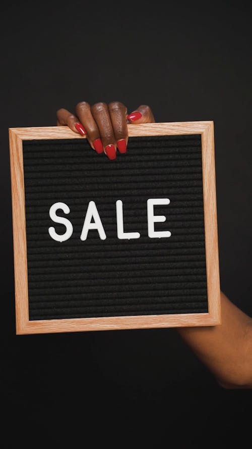 Person Holding a Frame with a Message Sale