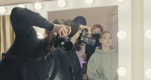 Man Taking Photo of a Woman while Getting Her Makeup Done