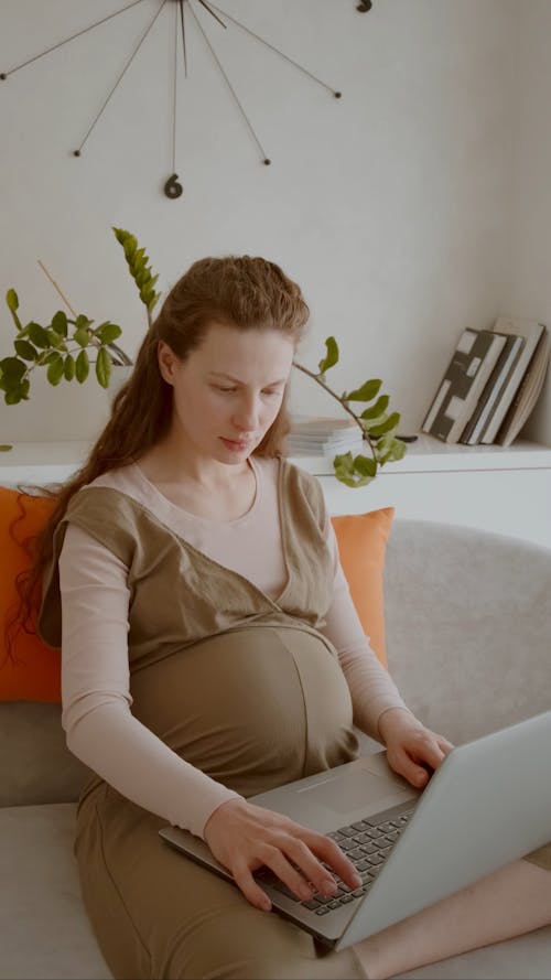 Pregnant Using Laptop While Seated On Sofa