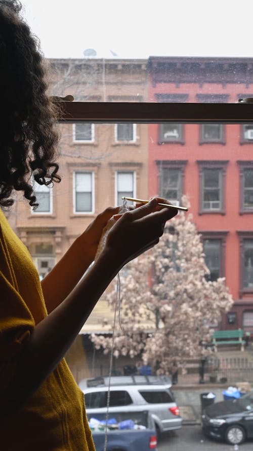 Woman Doing Crochet while Staring at the Window