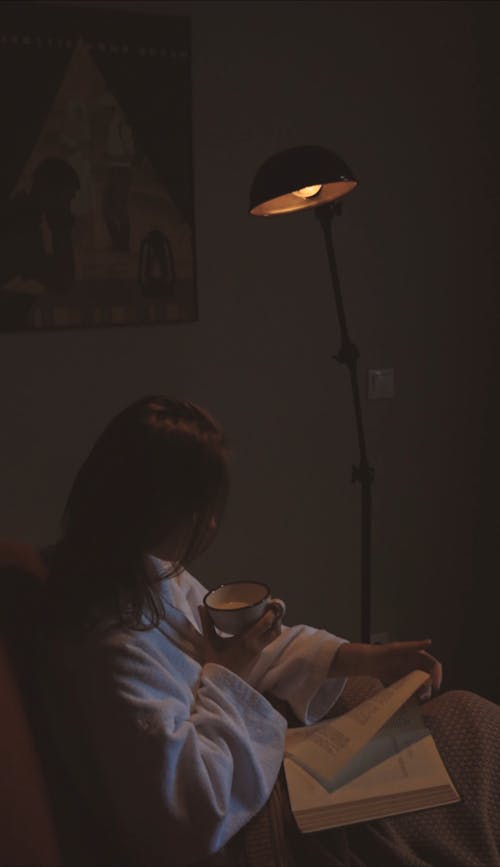 Woman Reading a Book while Holding a Mug