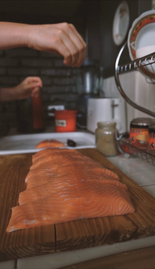 A Person Putting Seasoning on the Salmon