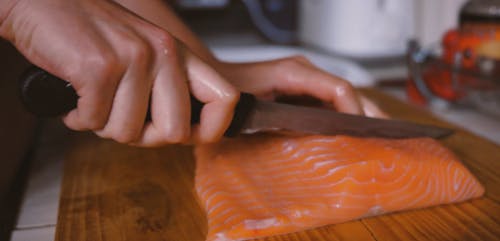 Person Slicing the Salmon