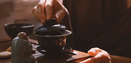 Person Making Tea on Traditional Teapot