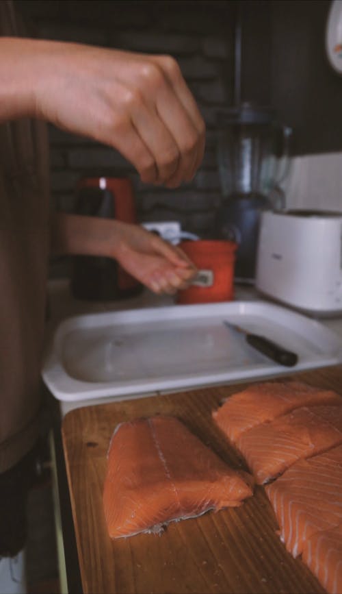 Person Seasoning the Salmon