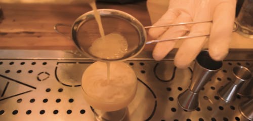 Person Using a Strainer on a Cocktail Drink