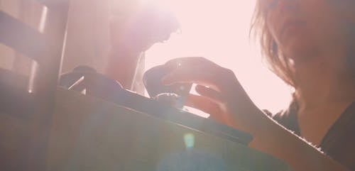 Sunlight from Behind a Female Pouring Liquid to a Cup