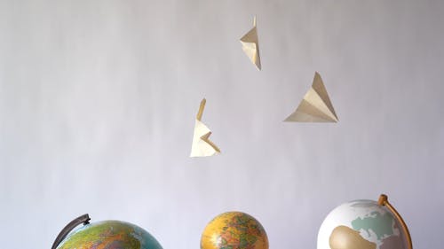 Paper Planes Hanging Over The Globe Spheres