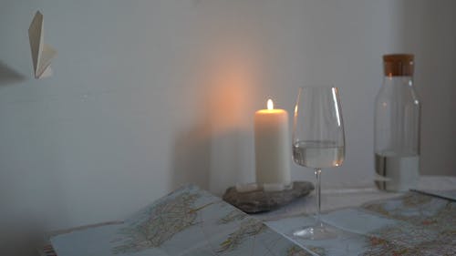 A Lighted Candle Over A Spread Paper Map