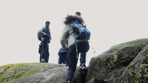 Man Helping Woman Climb a Rock