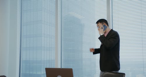 A Man Talking on the Phone while Using His Laptop