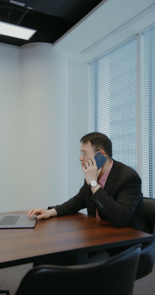Man Talking on the Phone While Using a Laptop