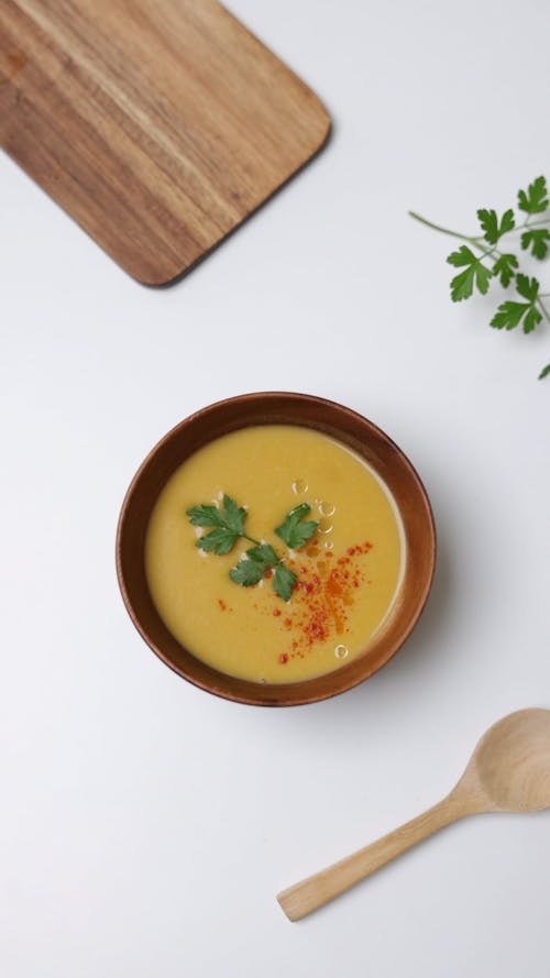 A Soup Dish in a Bowl and a Wooden Chopping Board
