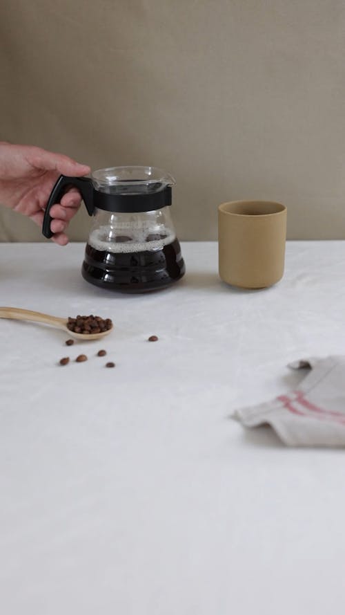 Pouring Brewed Coffee on Brown Cup