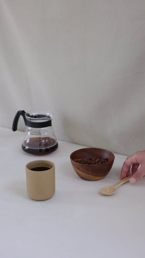A Person Scooping Coffee Beans in a Wooden Bowl