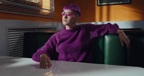Woman with Purple Hair and Sweatshirt Sitting in the Bistro